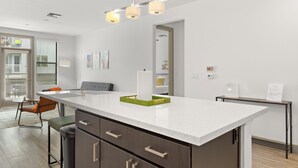 Eine moderne Küche mit weißer Arbeitsplatte, dunklen Schränken und einem grünen Akzent.