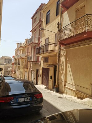 Una calle estrecha con un coche aparcado y edificios con balcones.