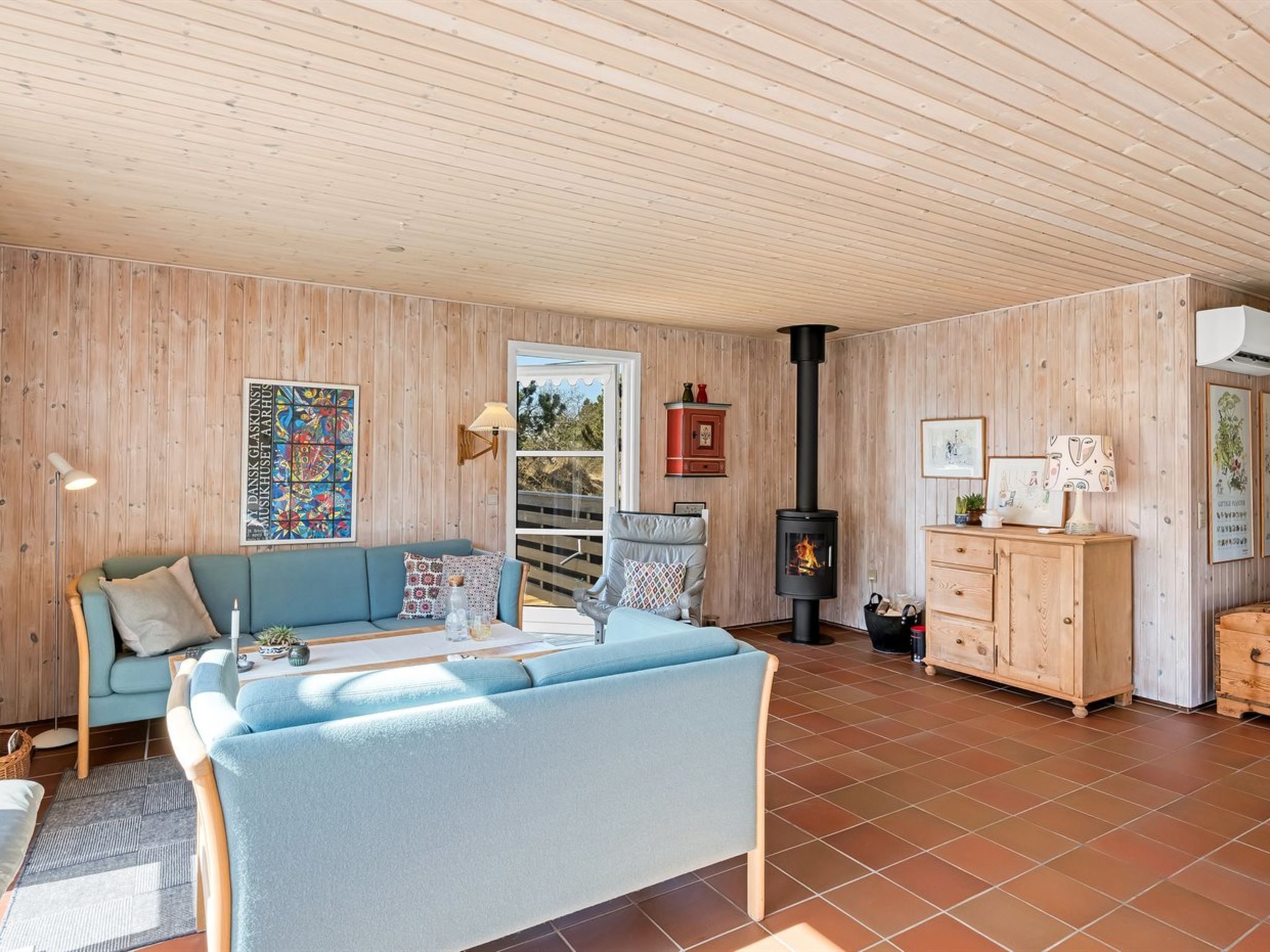 Un salon chaleureux avec un canapé bleu, un meuble en bois et une cheminée.