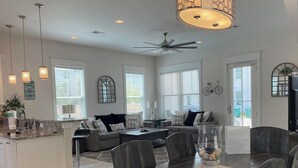 A spacious living room with a dark wood dining table, a grey sofa, and a ceiling fan. - 🦩Book Me Baby! 30A Oasis~Private Heated Pool~Pet-Friendly🦩 (Santa Rosa Beach)