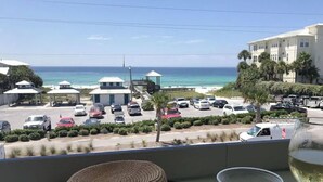 A balcony with a view of a beach, a parked car, and a glass of white wine. - 🦩Book Me Baby! 30A Oasis~Private Heated Pool~Pet-Friendly🦩 (Santa Rosa Beach)
