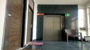 Un pasillo con puerta de madera, suelo de baldosas, un banco y una puerta numerada con el número 3.