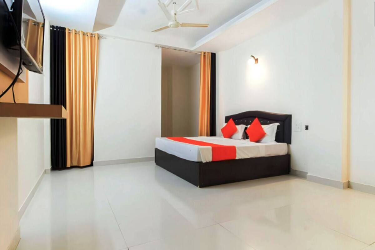 A bedroom with a bed, curtains, a ceiling fan, and a light fixture.