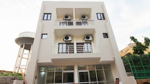 Un edificio de varios pisos con balcones, ventanas grandes y unidades de aire acondicionado.