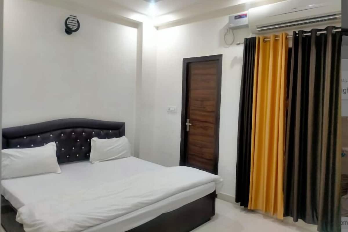 A bedroom with a bed, a door, and an air conditioning unit.