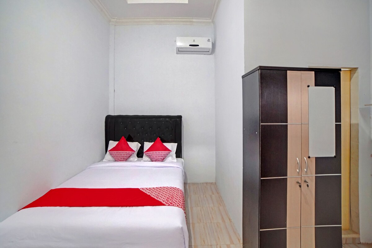 A bedroom with a bed, a wardrobe, and an air conditioning unit.