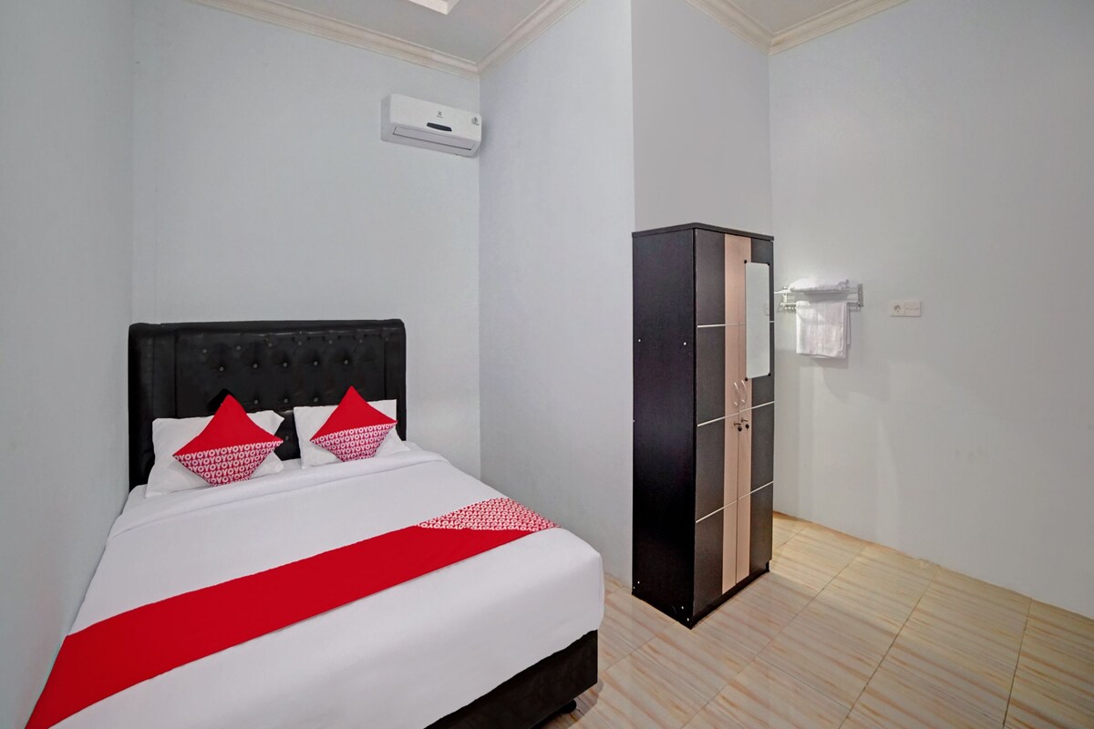 Ein Hotelzimmer mit Bett, Schrank, Wandklimaanlage und Lichtschalter.