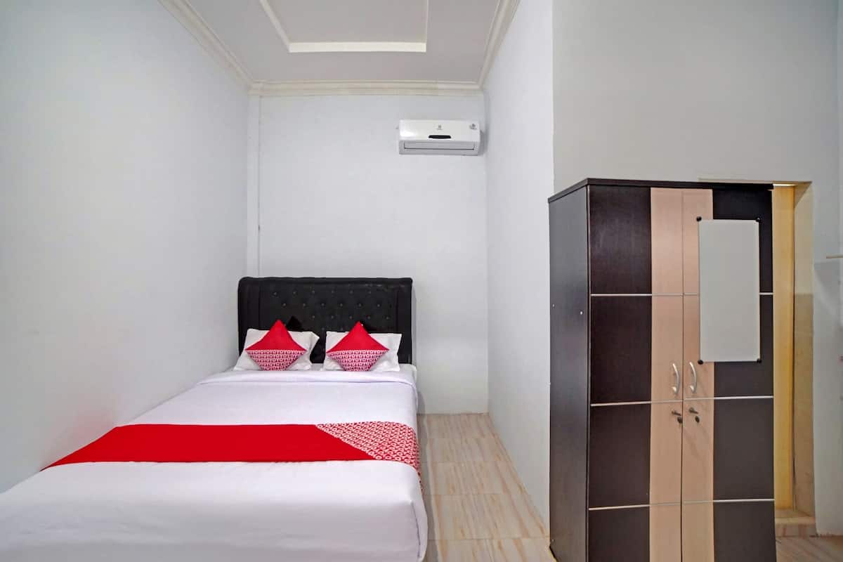 Hotellihuone, jossa on sänky, vaatekaappi ja ilmastointilaite.