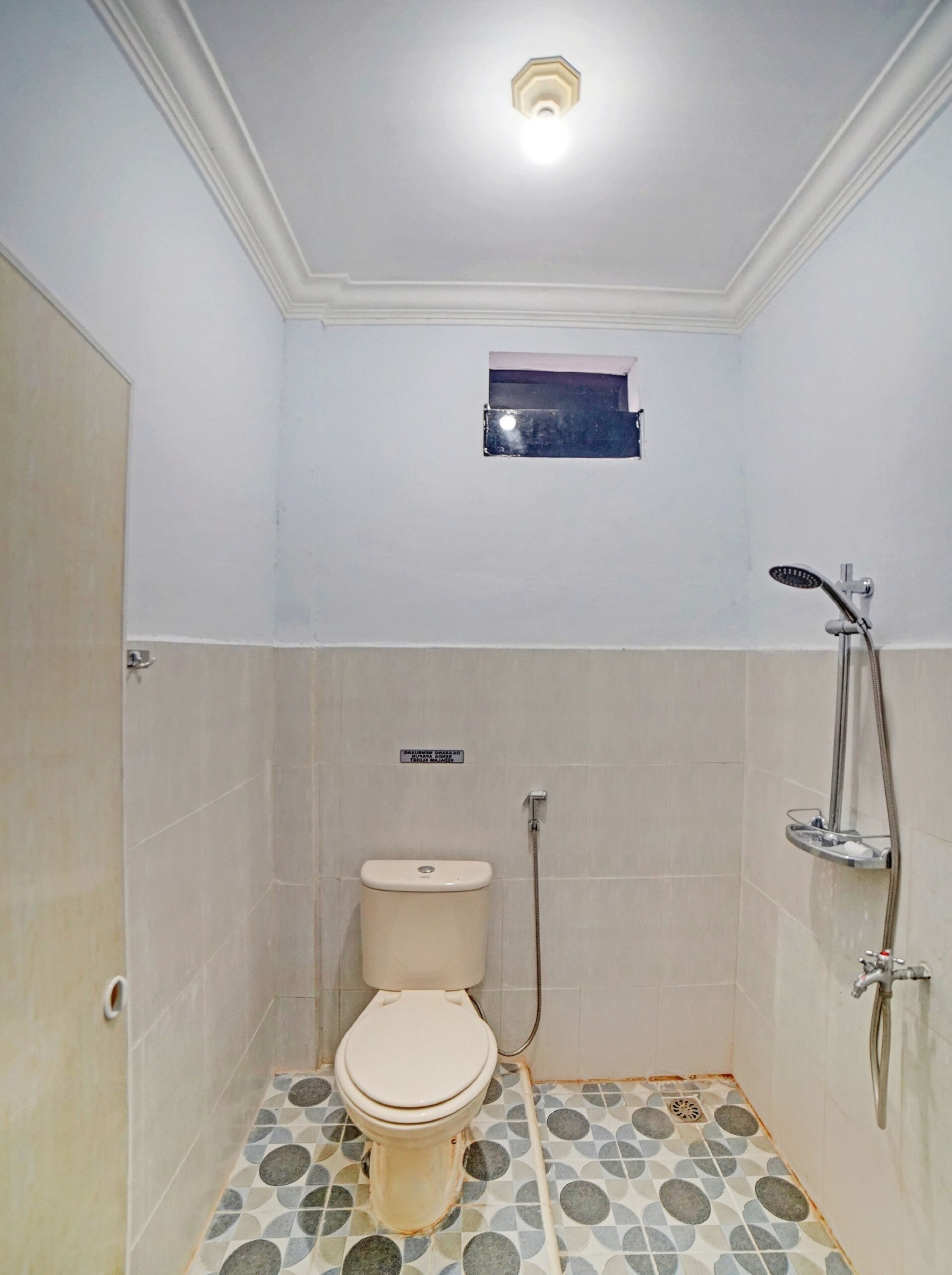 Un bagno piccolo rivestito di piastrelle, con un water, una doccia e un piccolo oblò.
