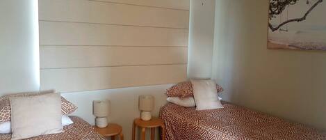 A hotel room with two beds, a nightstand, a lamp, and a painting on the wall.
