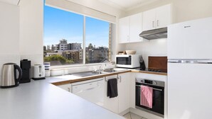 Una cucina moderna con mobili bianchi, un bollitore in acciaio inossidabile, un tostapane, un forno a microonde e un piano cottura.