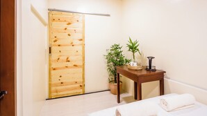 A hotel room with a wooden door, a small table with a plant, and a bed with towels. - ALONA BEACH SIDE INN (Panglao)