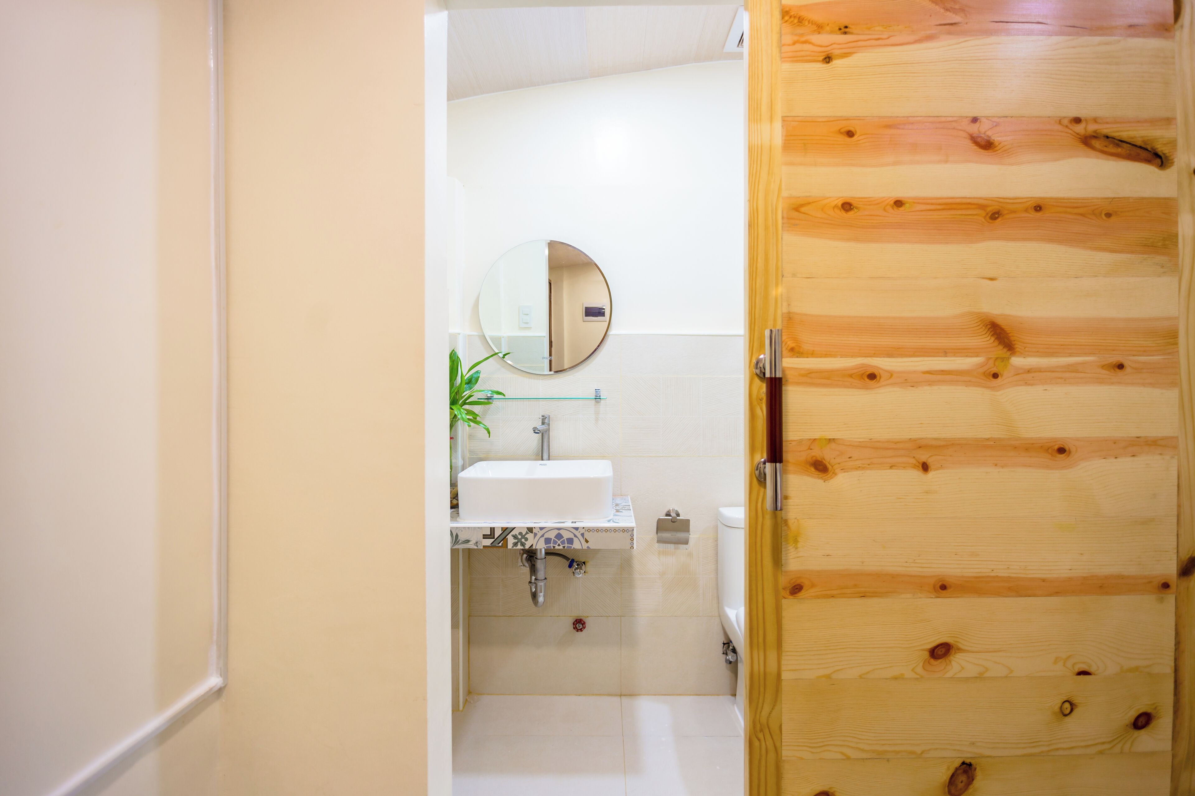 Une salle de bain avec une porte en bois, un lavabo, un miroir et des toilettes.