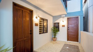A hallway with a wooden door, a potted plant, and a tiled floor. - ALONA BEACH SIDE INN (Panglao)