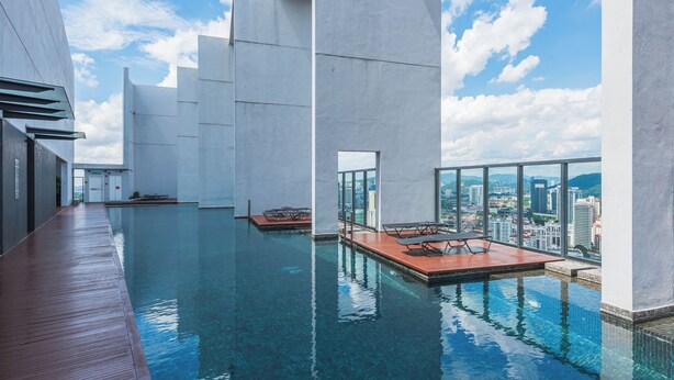 Una piscina a sfioro con terrazza in legno, architettura moderna e vista sulla città.