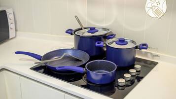 A kitchen with a stove, pots, and pans.