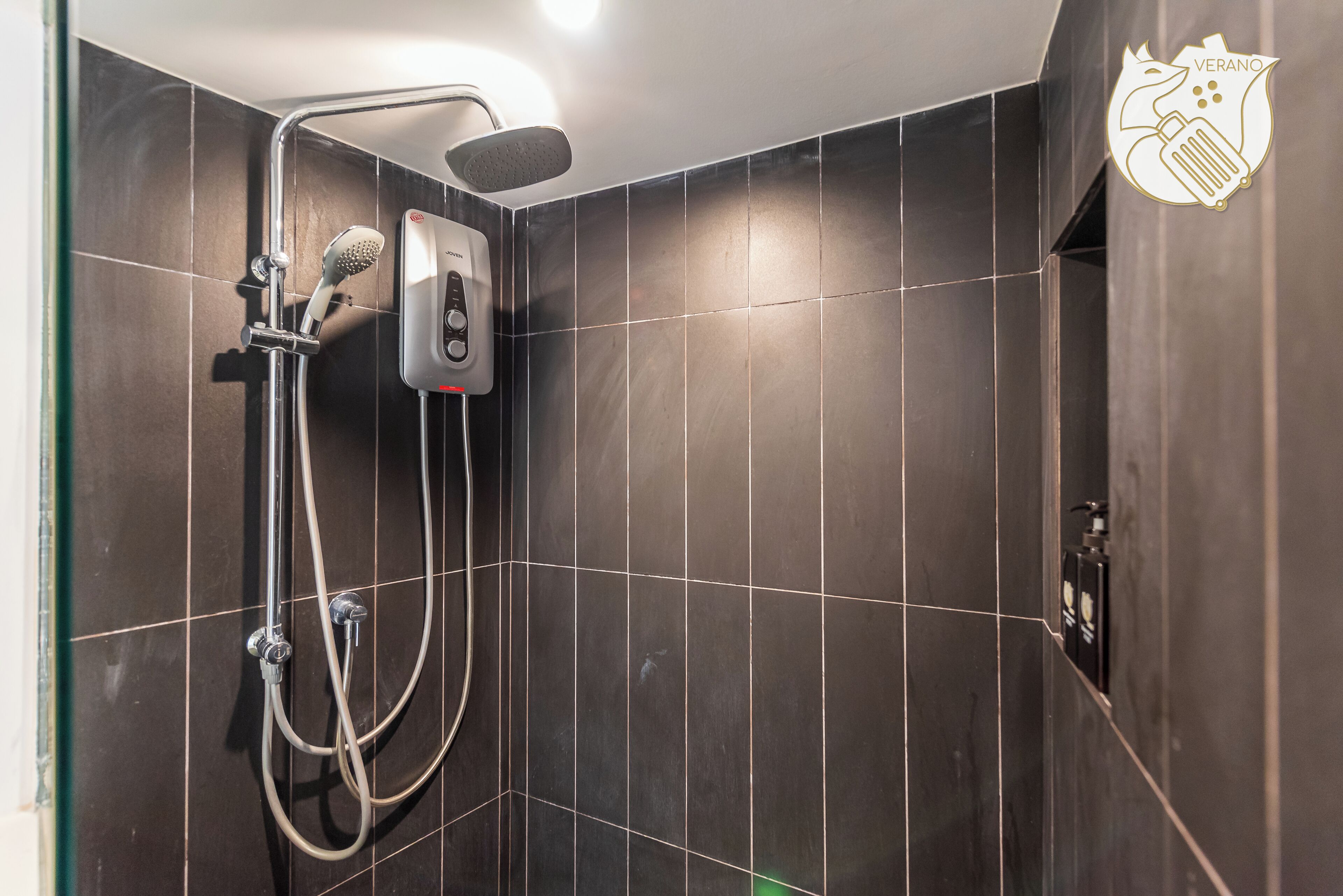 Een douche met een handdouche en een bedieningspaneel aan de muur.