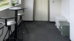 A small office space with a window, a desk, two chairs, an elevator, and a trash bin. - Hotel Justice (Minamiuonuma)