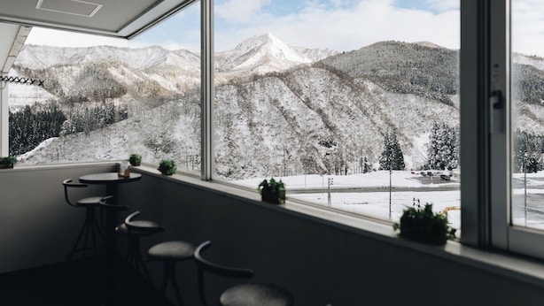 A room with a large window offering a view of snow-covered mountains. - Hotel Justice (Minamiuonuma)