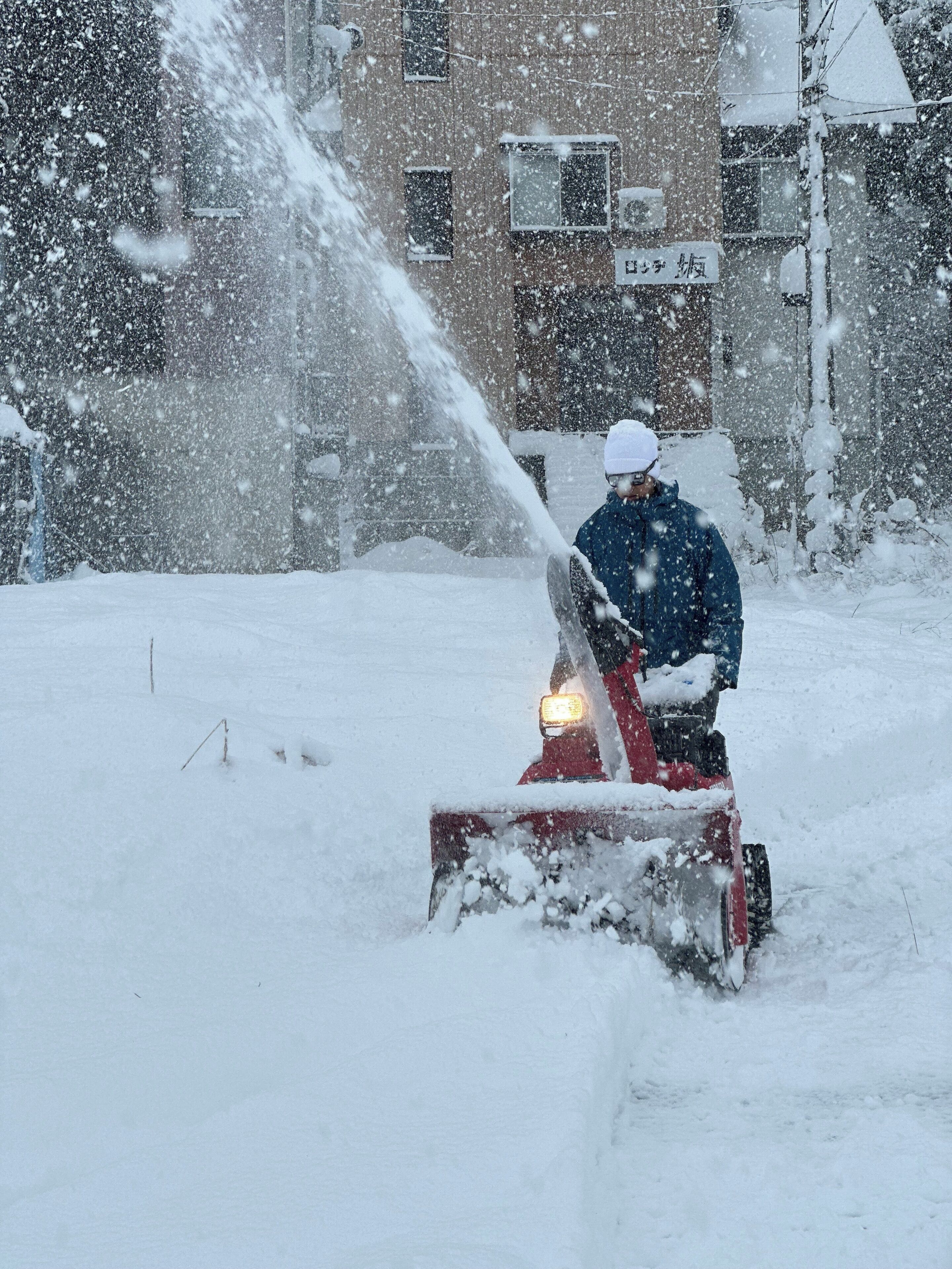 A person using a snow blower in a snowy environment.