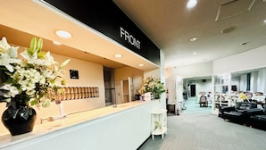 A reception area with a counter, a clock, and a sign that reads "FRONT". - Hotel Justice (Minamiuonuma)