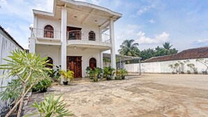 A two-story building with a balcony, potted plants, and a concrete courtyard. - OYO 90585 Saka Ganta Guest House Syariah (Terbanggi Ilir)