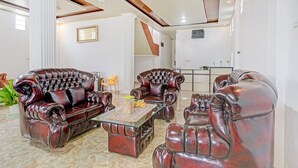A spacious living area with leather armchairs and a glass coffee table, featuring a modern ceiling design and a large window. - OYO 90585 Saka Ganta Guest House Syariah (Terbanggi Ilir)