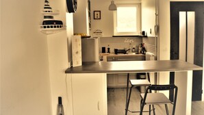 A compact kitchen with a central island, a small dining area, and a refrigerator.