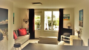A living room with a sofa, a coffee table, a TV, and a window with curtains.