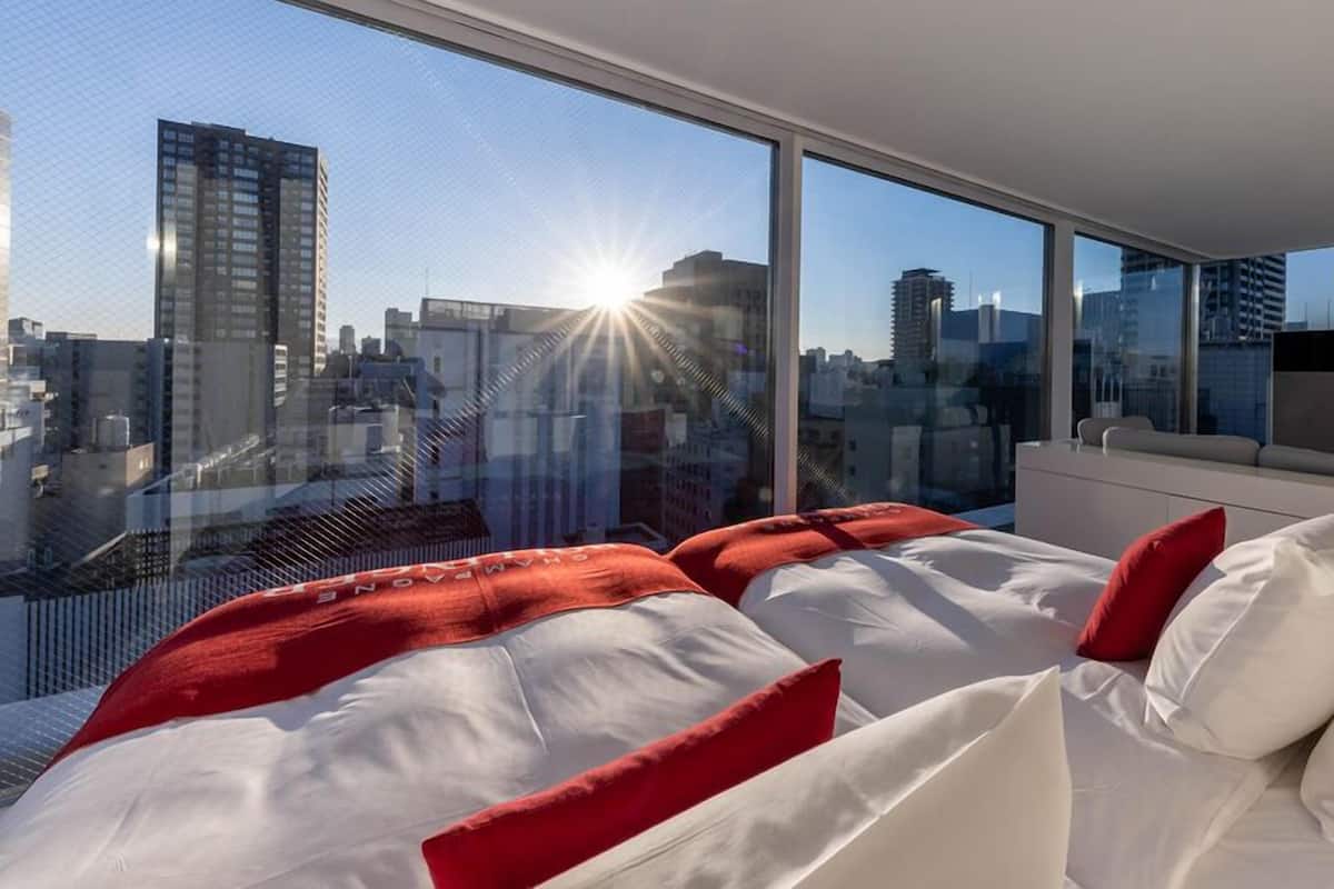 A modern hotel room with a large bed, a sofa, and a TV.