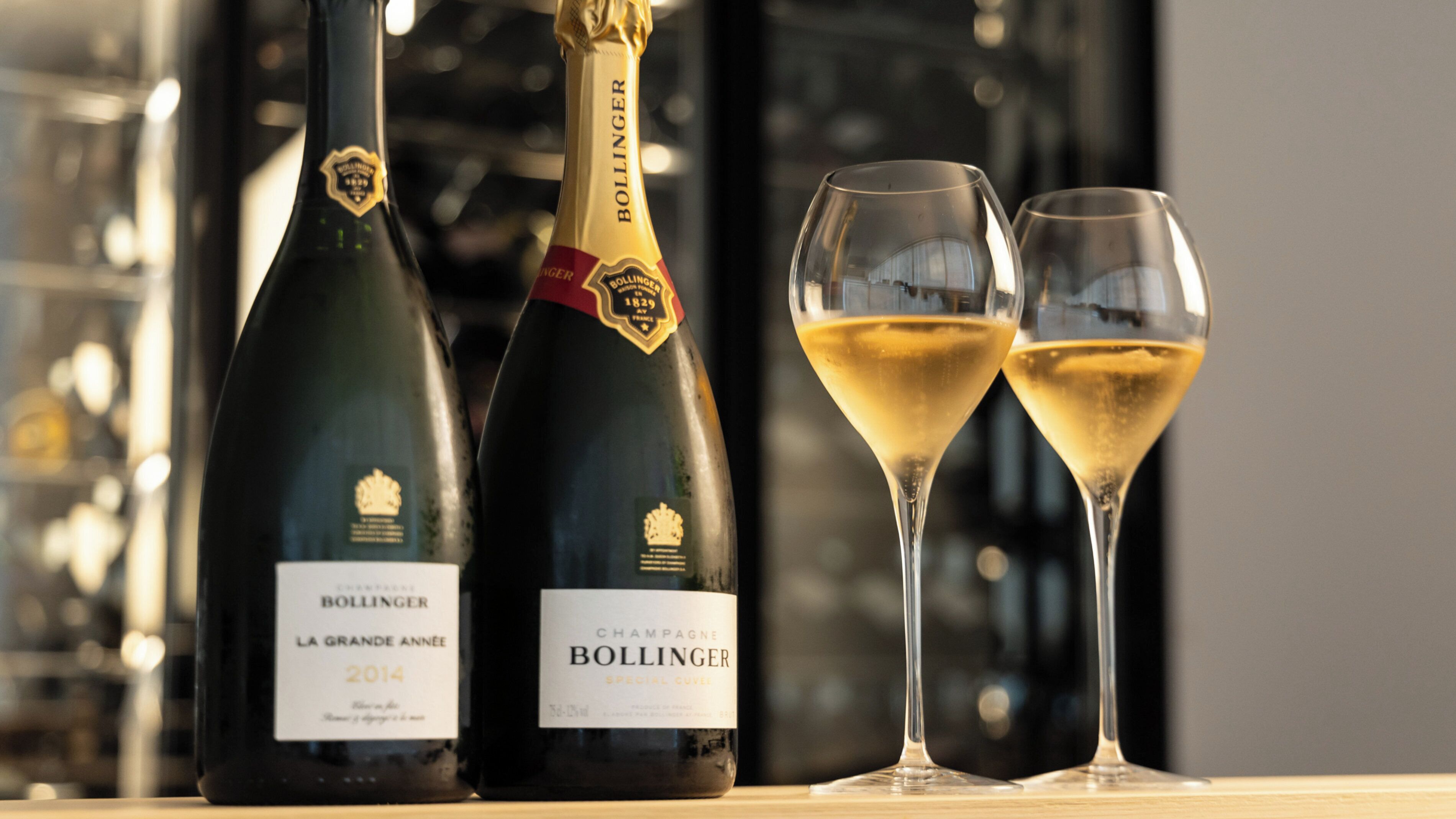 Two bottles of Bollinger champagne and two glasses filled with champagne.