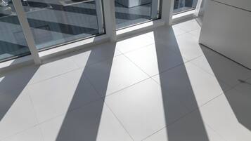 A modern room with large windows, white tiled flooring, and a white cabinet.