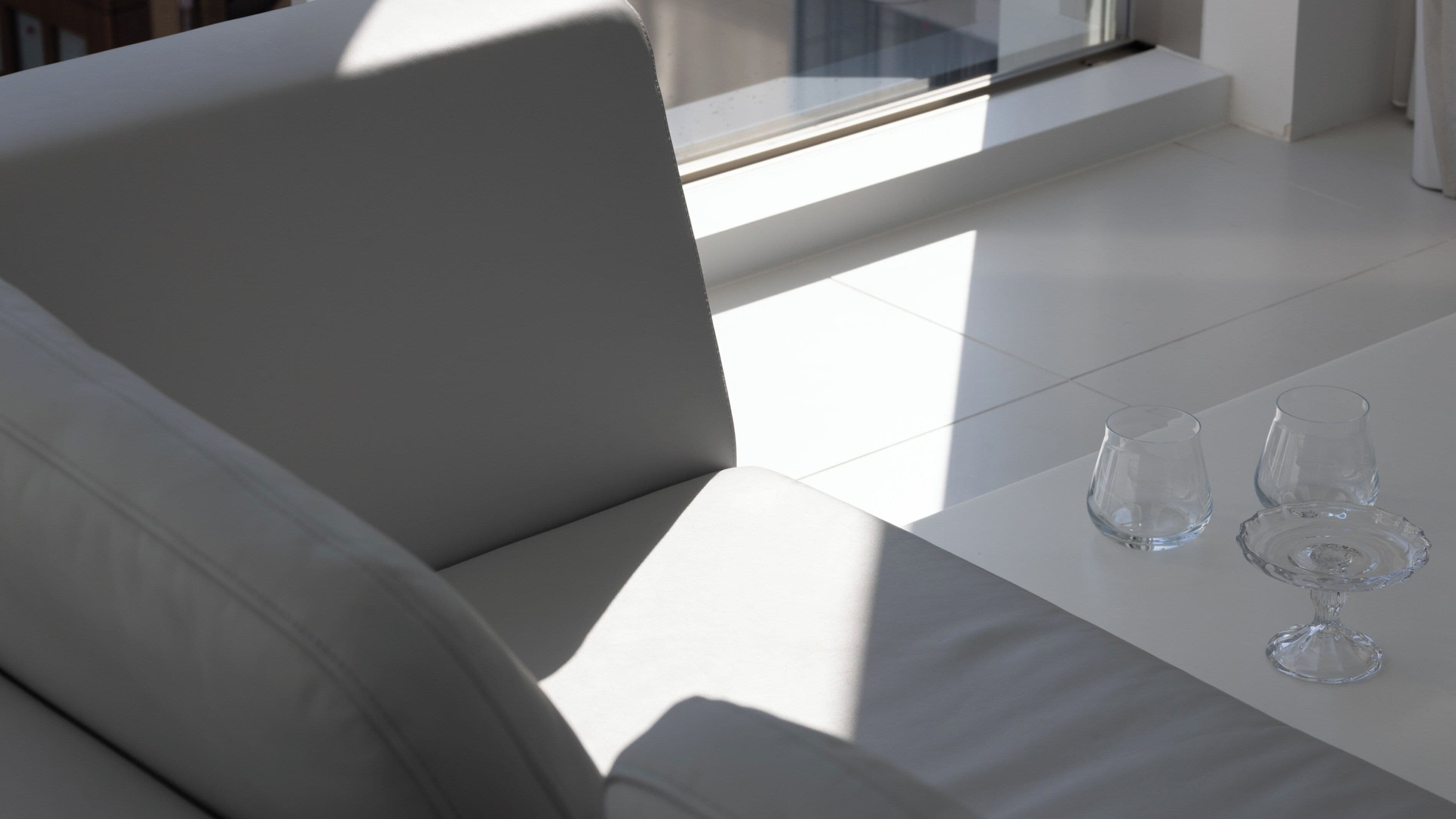 Une pièce moderne et minimaliste, avec un canapé blanc et une table en verre.