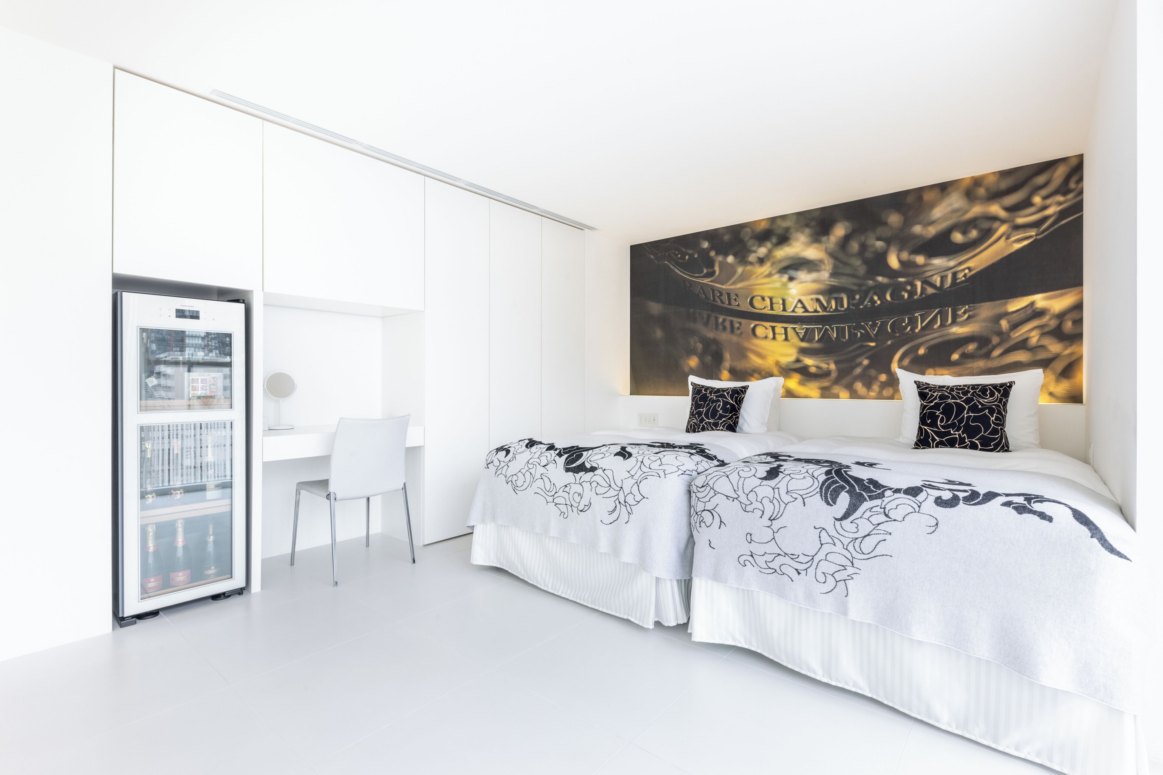 A modern bedroom with a bed, a desk, and a refrigerator.