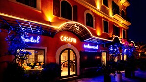 Un hotel con un letrero de neón, una entrada en arco y una fachada bien iluminada.