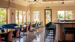 Un restaurante espacioso con techos altos, ventanas amplias y diversas opciones de asientos, incluyendo mesas redondas y taburetes de bar.