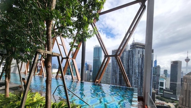 A rooftop infinity pool with a city skyline view, surrounded by greenery and metal structures. - High Floor KL View Scarletz Suite (Kuala Lumpur)