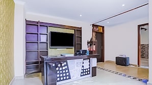 Uma mesa de recepção com televisão de tela plana, uma pequena área de estar e uma porta que dá para um corredor.