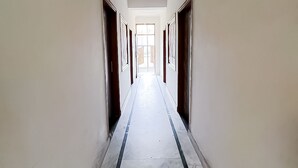 Um corredor comprido e estreito com piso de mármore e paredes brancas.
