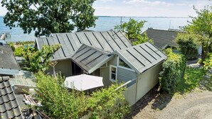 A small, single-story house with a sloped roof, surrounded by greenery and a view of a body of water. - "Snari" - 10m from the sea by Interhome (Svendborg)