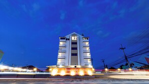 Un grand immeuble moderne, facilement reconnaissable à son panneau « B2 » bien visible, qui semble être un hôtel ou un immeuble de bureaux, avec de nombreux étages et des balcons.