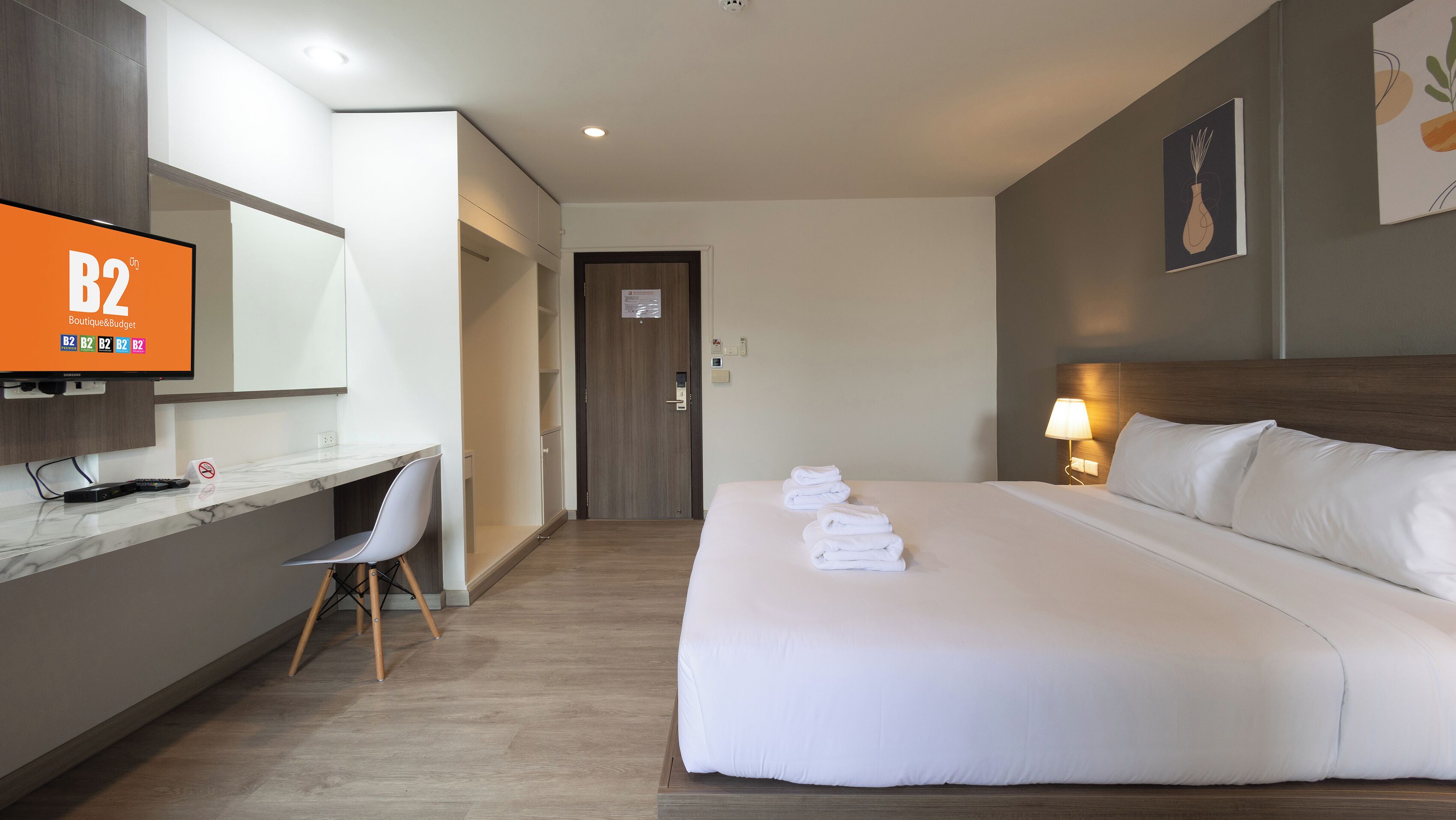 Ein Hotelzimmer mit einem Bett, einem Schreibtisch mit Stuhl, einem Fernseher und einer Tür.
