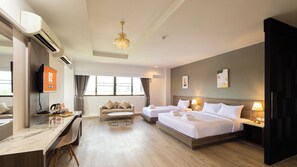 Een hotelkamer met twee bedden, een bureau, een stoel, een televisie en een kroonluchter.
