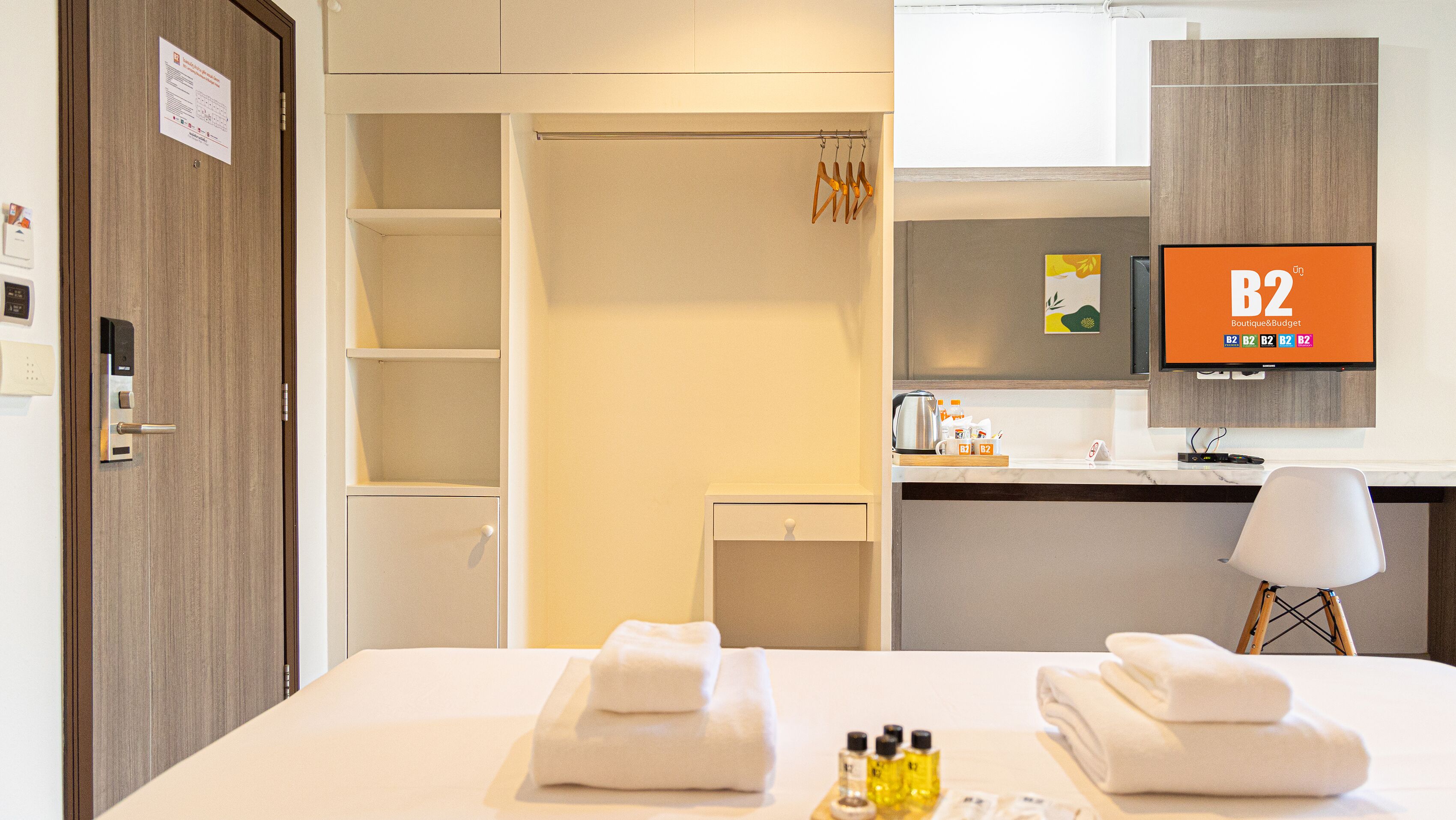 A hotel room with a bed, a desk, a chair, a television, and a bathroom.
