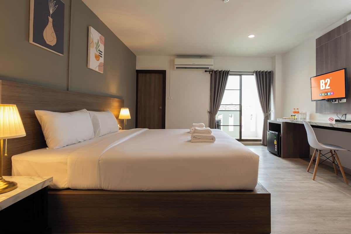 Une chambre d’hôtel équipée d’un lit, d’une lampe de chevet, d’un bureau avec une chaise, d’un téléviseur et d’un appareil de climatisation.