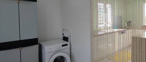 Ein Waschbereich mit Waschmaschine, Schrank und einer Schiebetür.