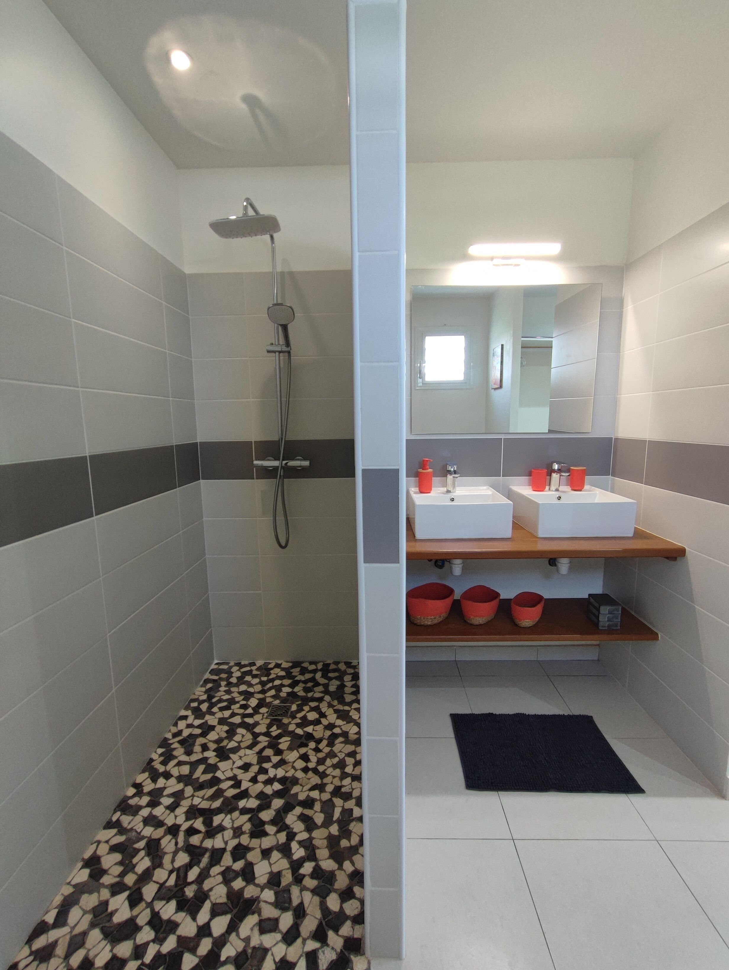 Un baño moderno con dos lavamanos, una ducha y suelo de baldosas.