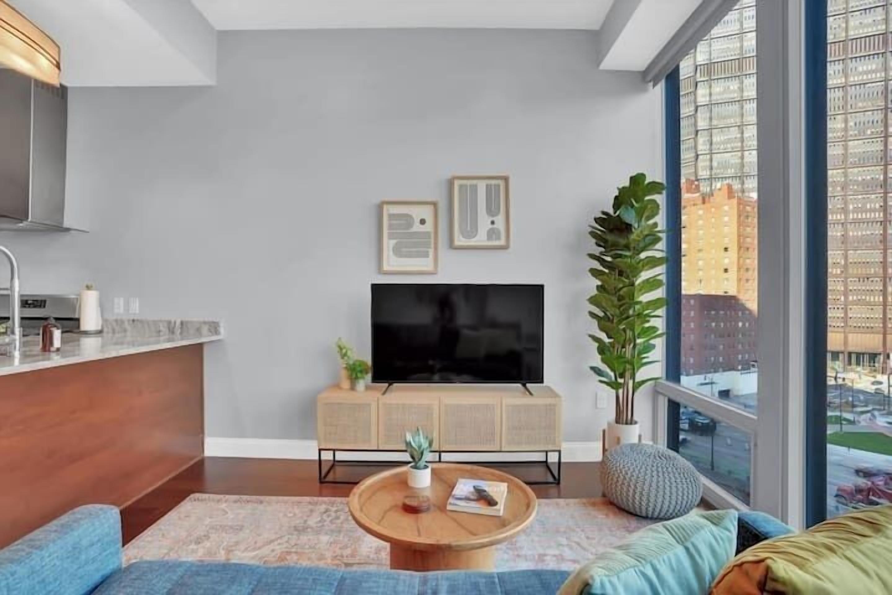 A modern living room with a large TV, a wooden coffee table, and a sofa.