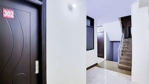 A hallway with a door labeled '302', a staircase, and a modern interior design. - Roomshala 118 Hotel Acclaim 7 sky (New Delhi)