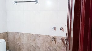 A bathroom with a toilet, a pink bucket, a towel rack, and a shower area. - Roomshala 118 Hotel Acclaim 7 sky (New Delhi)